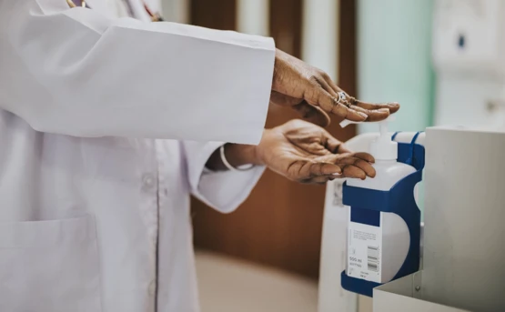 Woman in lab coat using hand sanitiser