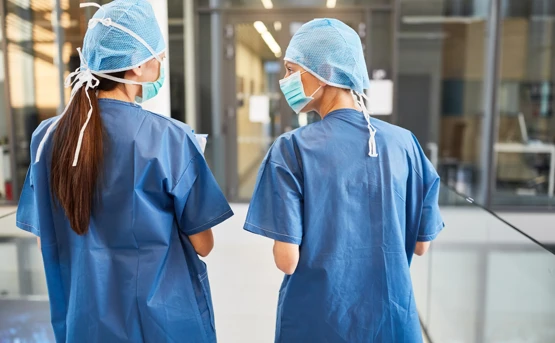 Two Doctors From Behind Wearing Scrubs And Masks