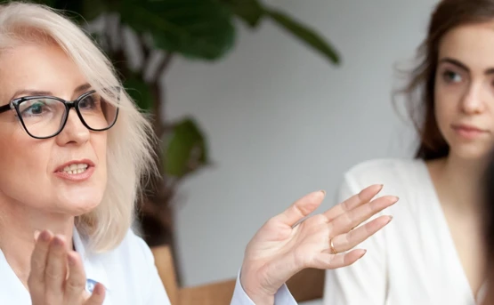 an older woman talks with hand movements to a younger woman