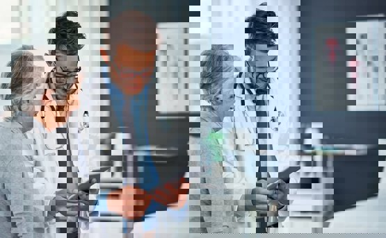 A medical professional talks to a patient whilst looking at a tablet 