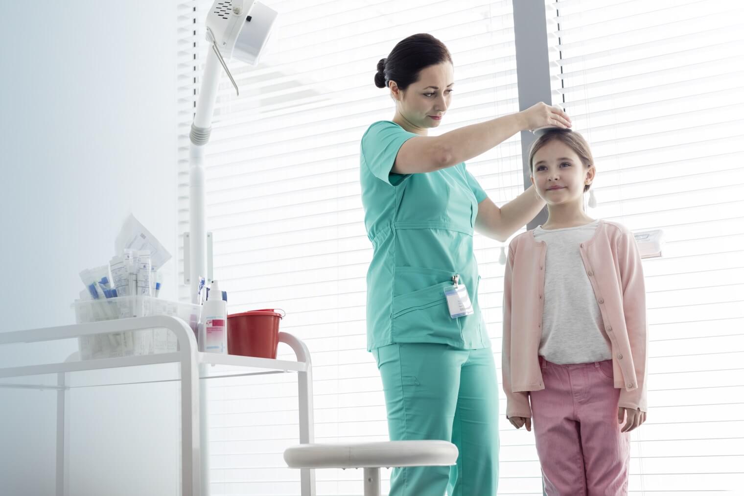 A doctor measures a young girl