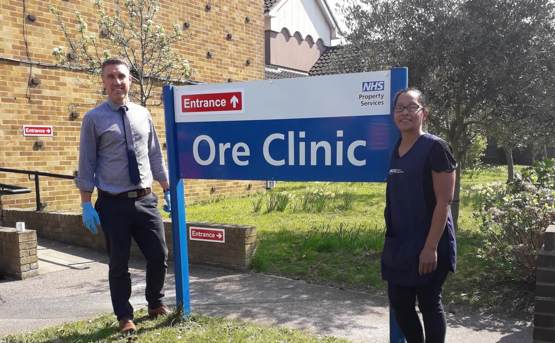 Two hospital workers stood by a sign for Ore clinic 