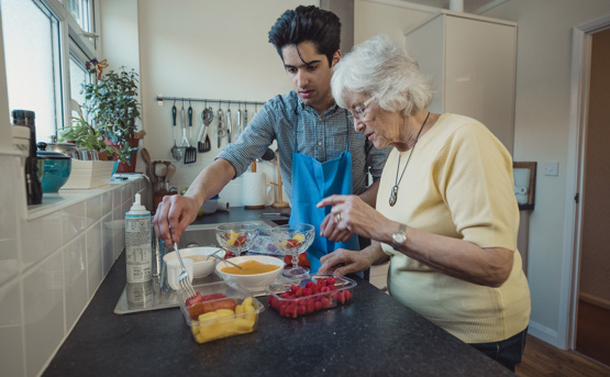 Young man and elderly woman cooking 