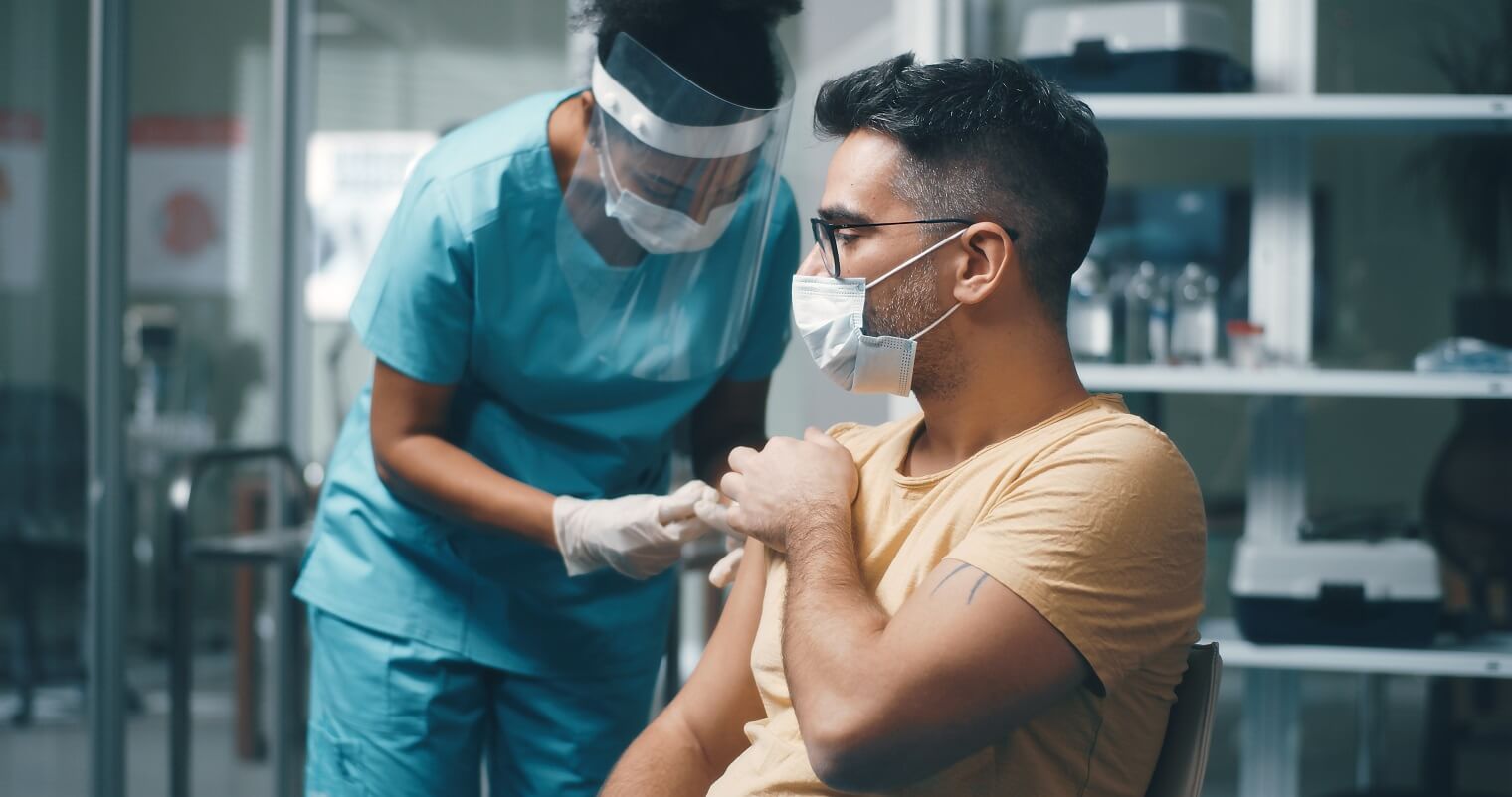 man in face mask being vaccination by a doctor