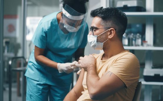 man in face mask being vaccination by a doctor