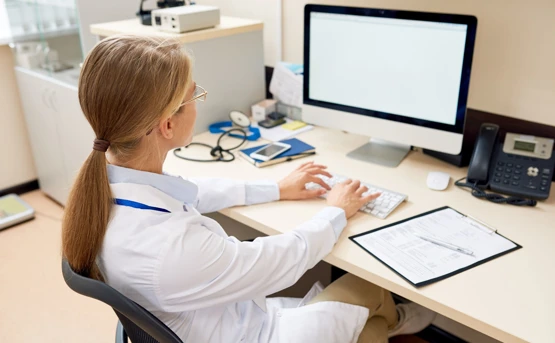 Blonde female doctor working on the computer 