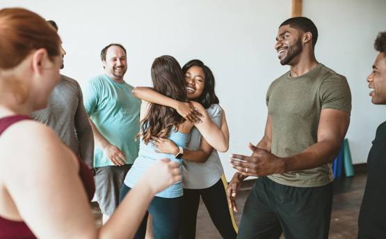 Stock image of a group of people in an exercise class where 2 women are hugging