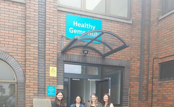 Four women standing at the front of Healthy Gems Hub, smiling