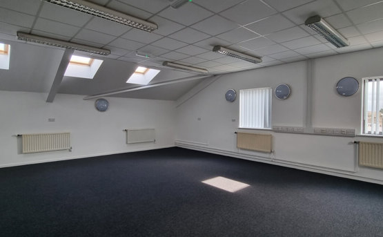 Large vacant room with a few windows and radiators