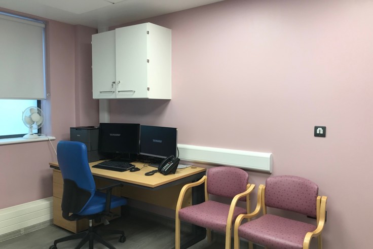 Pink GP room with desk and two chairs