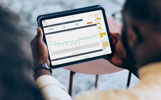 A person holds a tablet displaying a data dashboard with a line graph showing office space utilization.