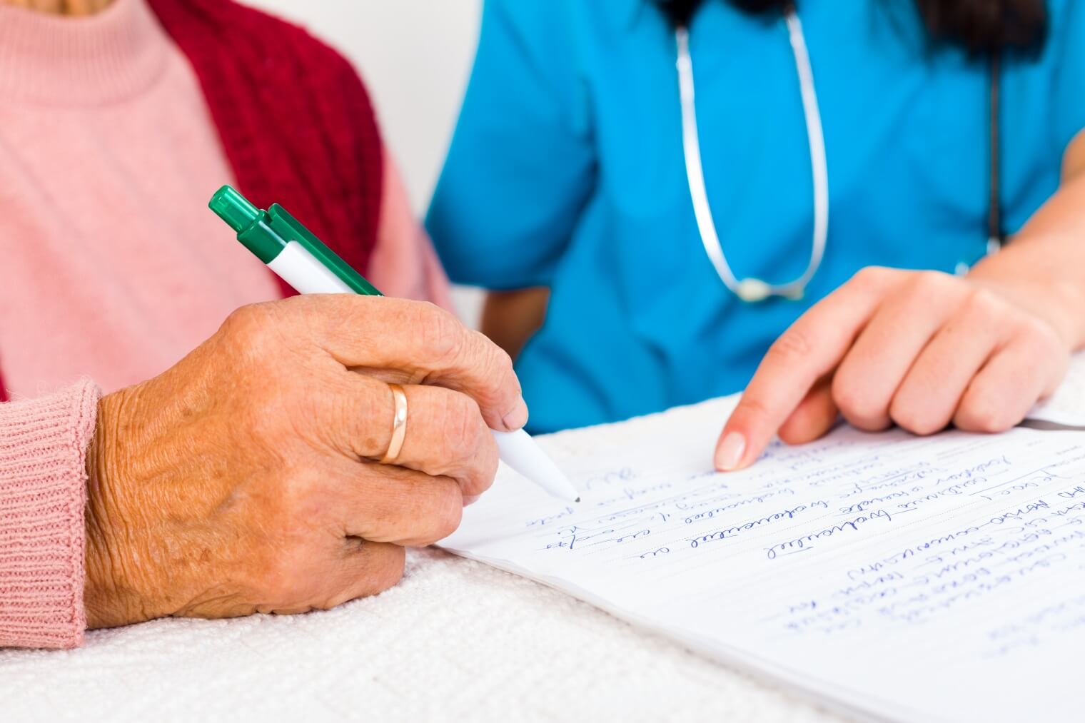 Elderly citizen filling out paperwork with the help of a healthcare professional