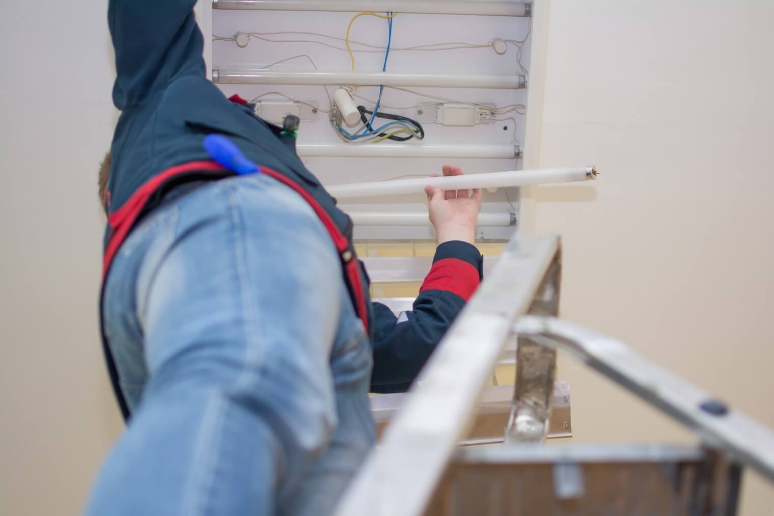 Image of electrician changing bulb in fluorescent strip light